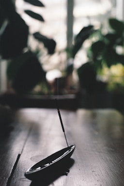 A serene workspace with traditional incense sticks burning beside a laptop and a jute bag in the background.
