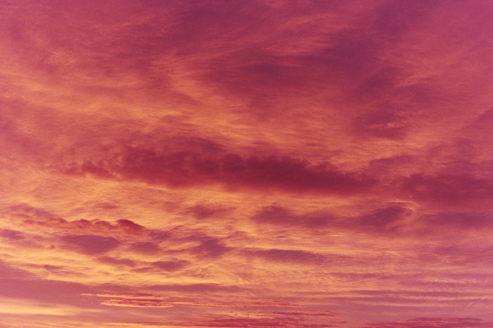 a plane flying in the sky at sunset