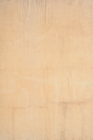 A textured beige surface with visible creases and subtle tonal variations, resembling aged or weathered parchment paper.
