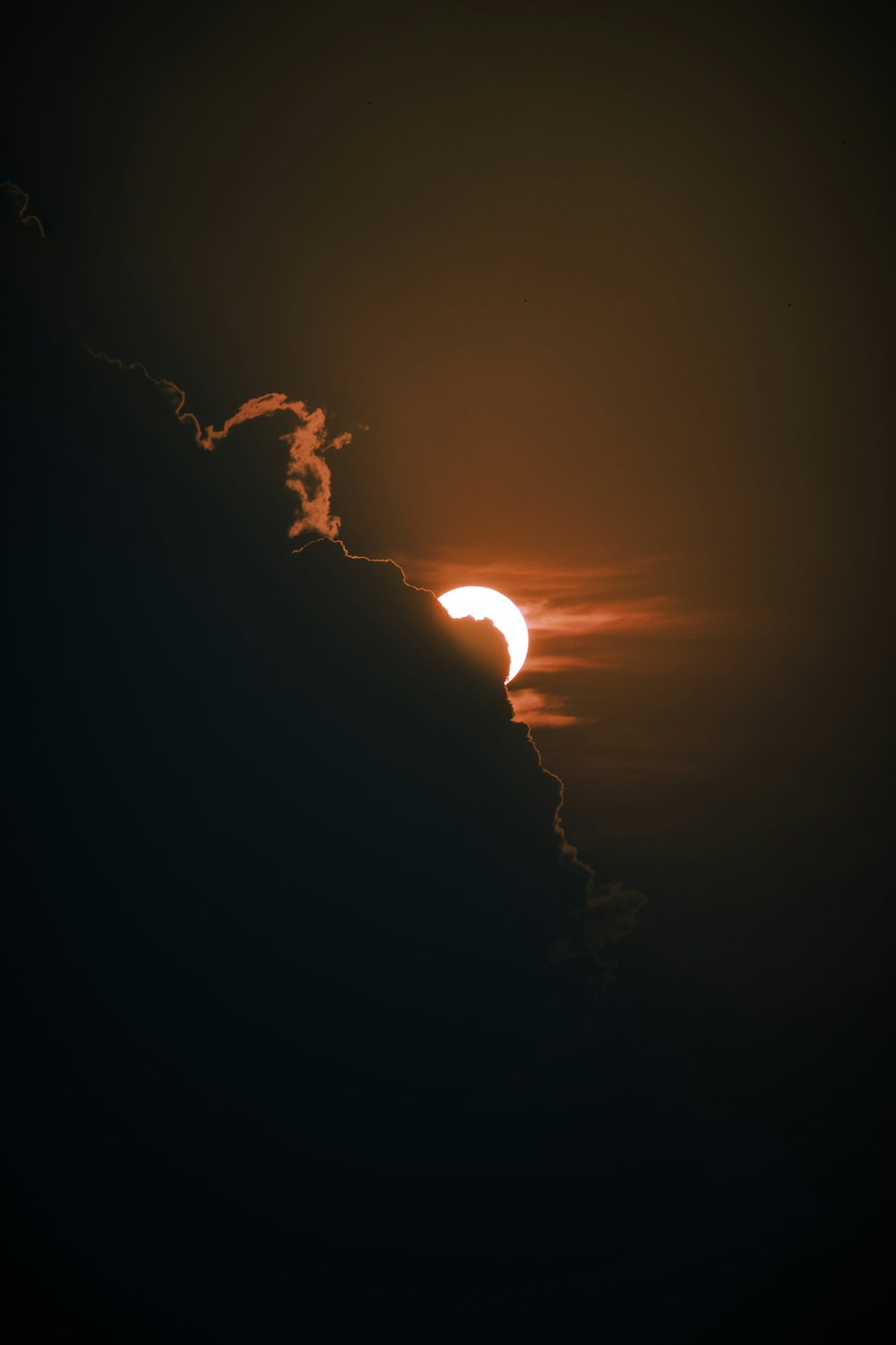 the sun is setting behind a cloud in the sky