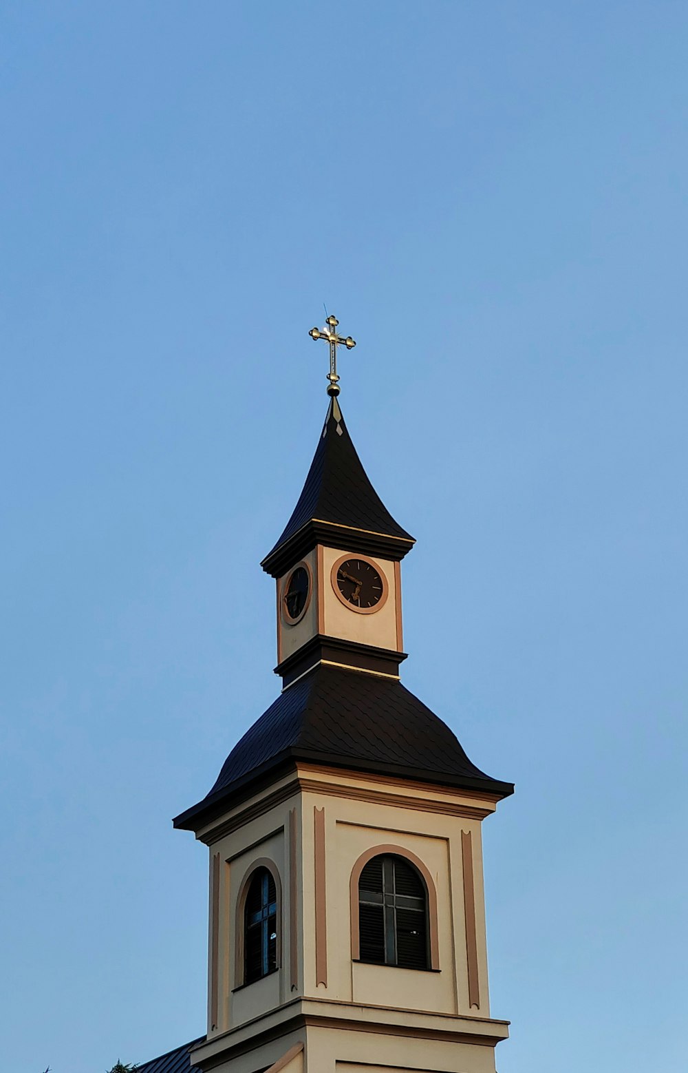 a clock tower with a cross on top of it