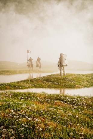 An astronaut in a spacesuit stands on a grassy field, facing away. In the distance, two figures on horseback with flags appear through the mist, creating a mysterious and surreal scene.