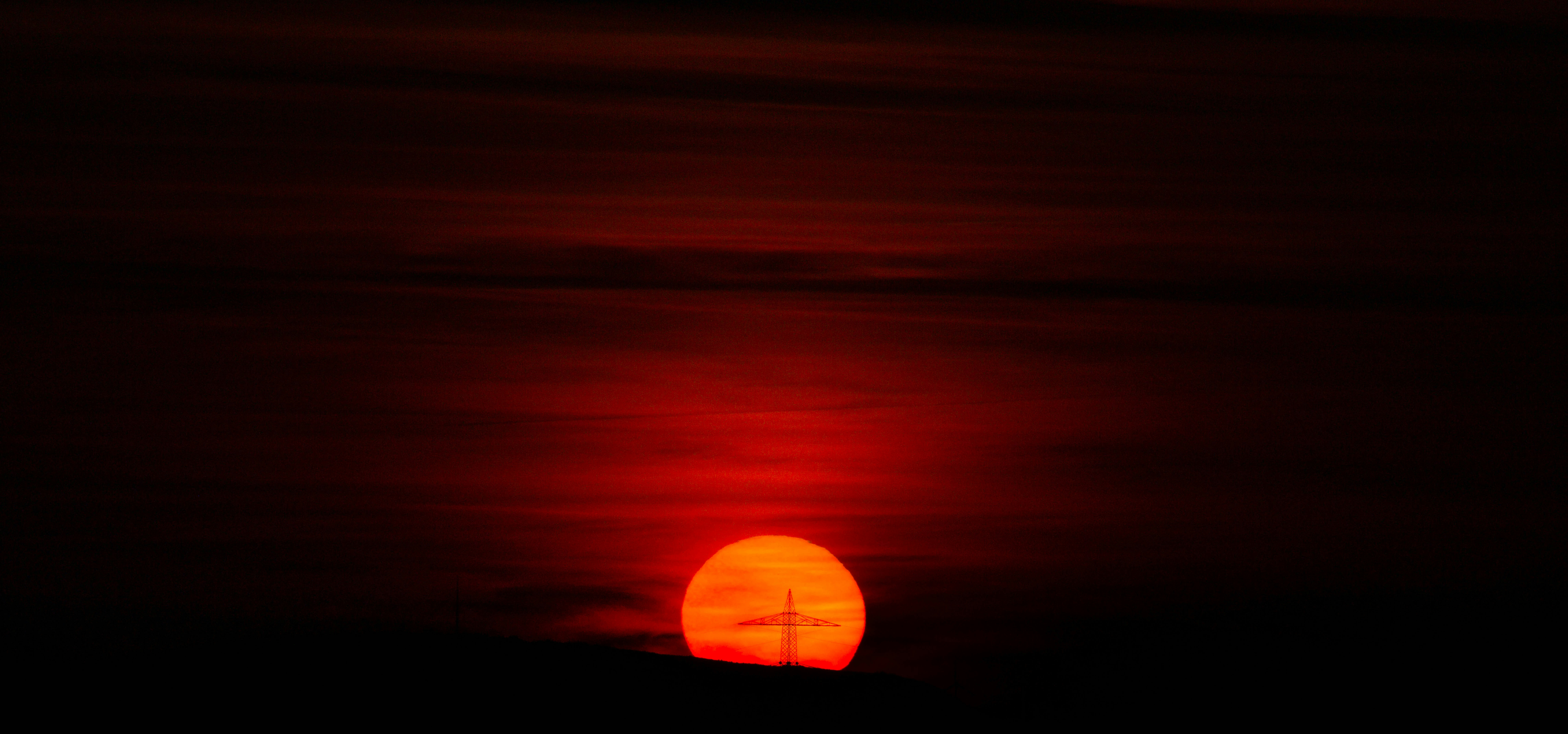 the sun is setting in the sky over a hill