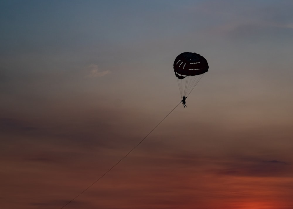 a person is parasailing in the sky at sunset