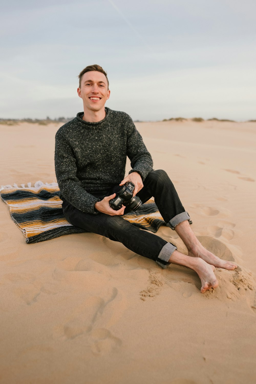 a man sitting in the sand with a camera