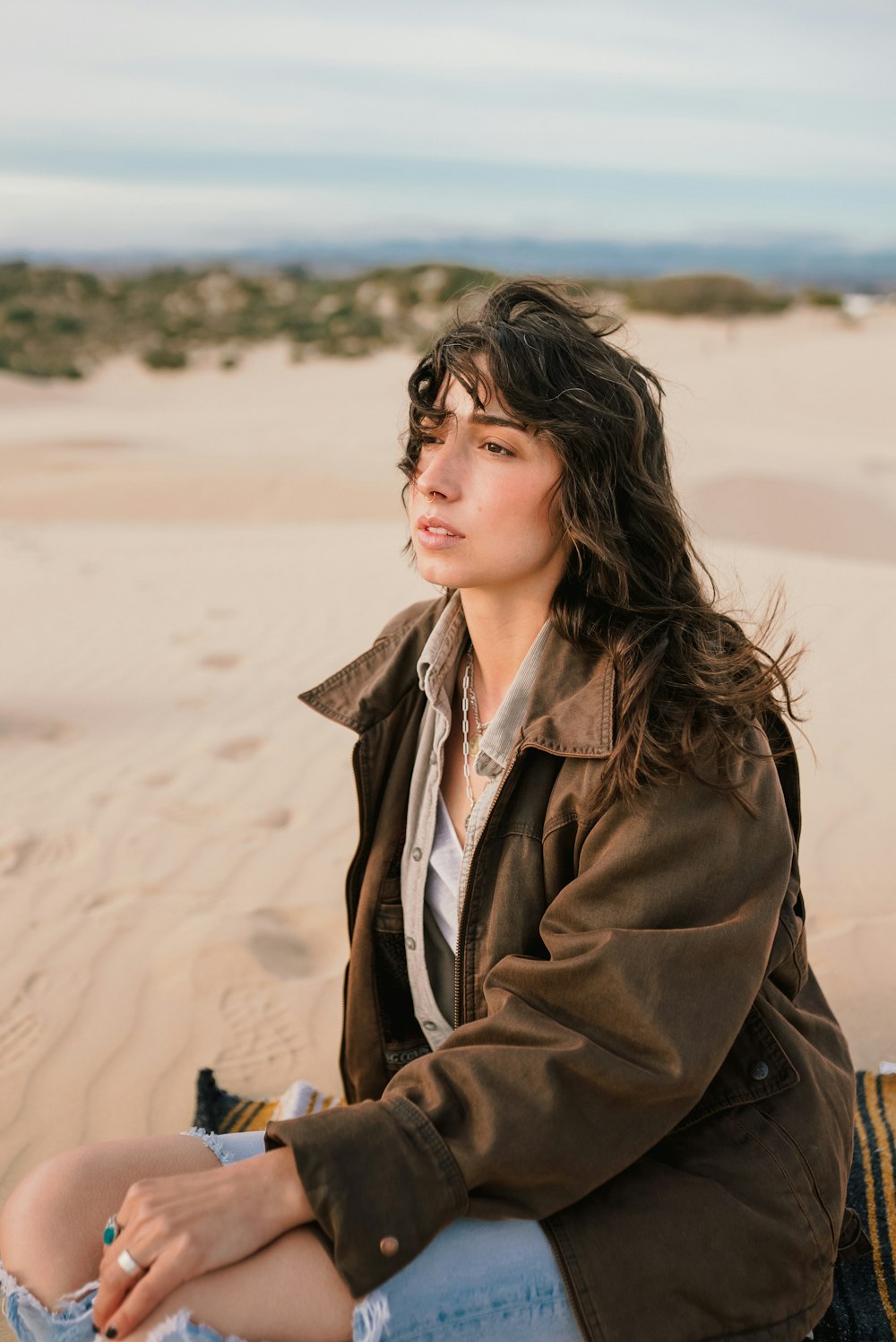 a woman sitting on top of a sandy beach