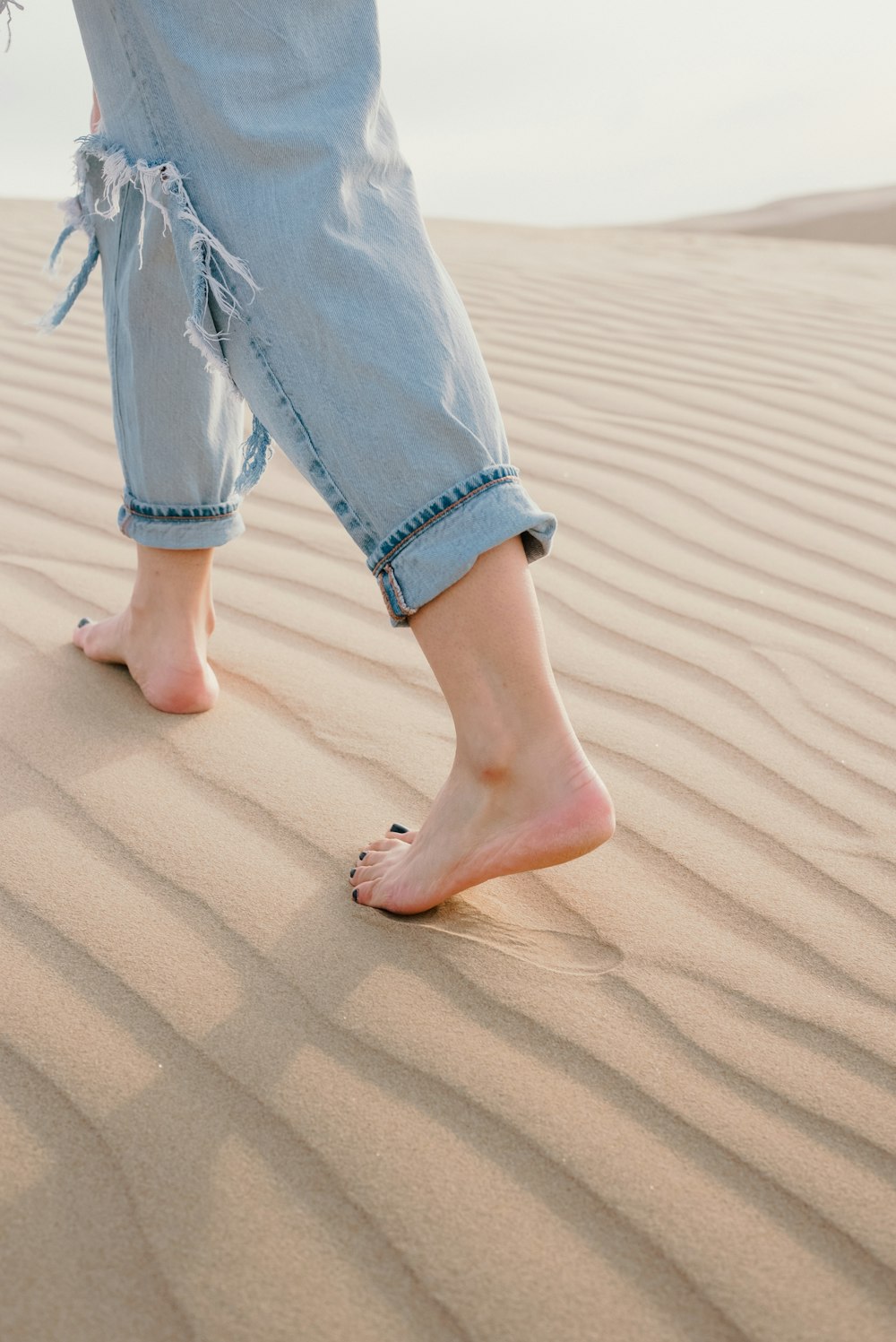 uma pessoa em pé no topo de uma praia de areia