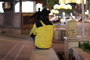 Close-up of a sleek black jacket draped over a city bench at dusk