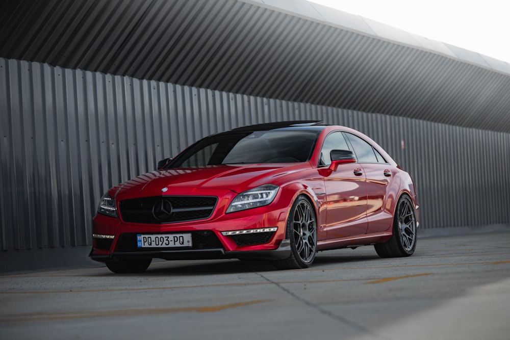 a red mercedes cla parked in front of a building