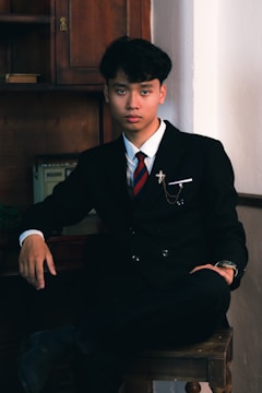 a man in a suit and tie sitting on a stool