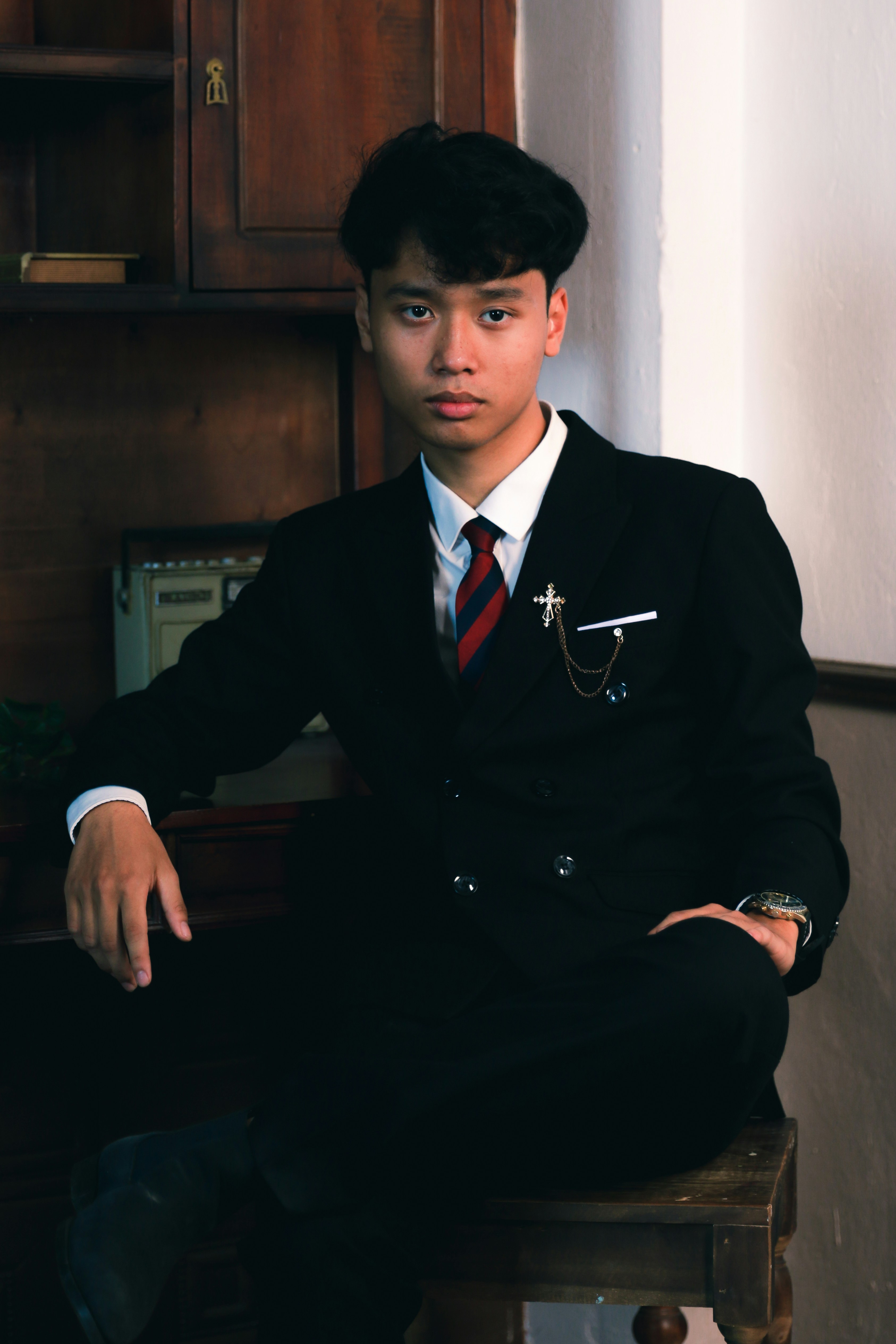a man in a suit and tie sitting on a stool