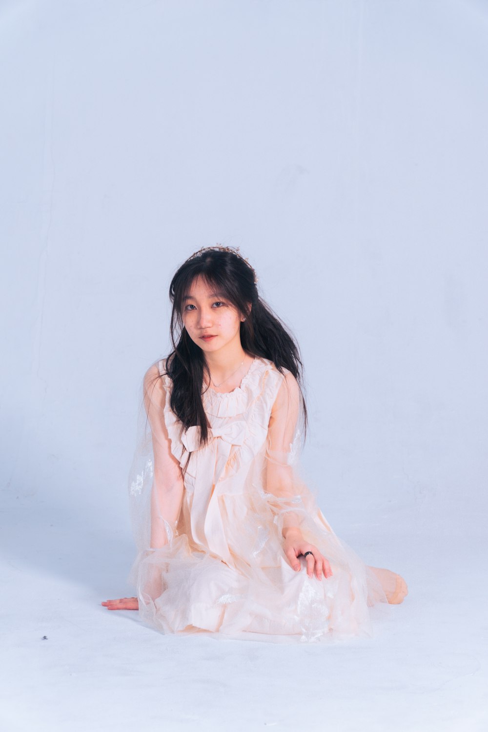 a girl in a white dress sitting on the ground