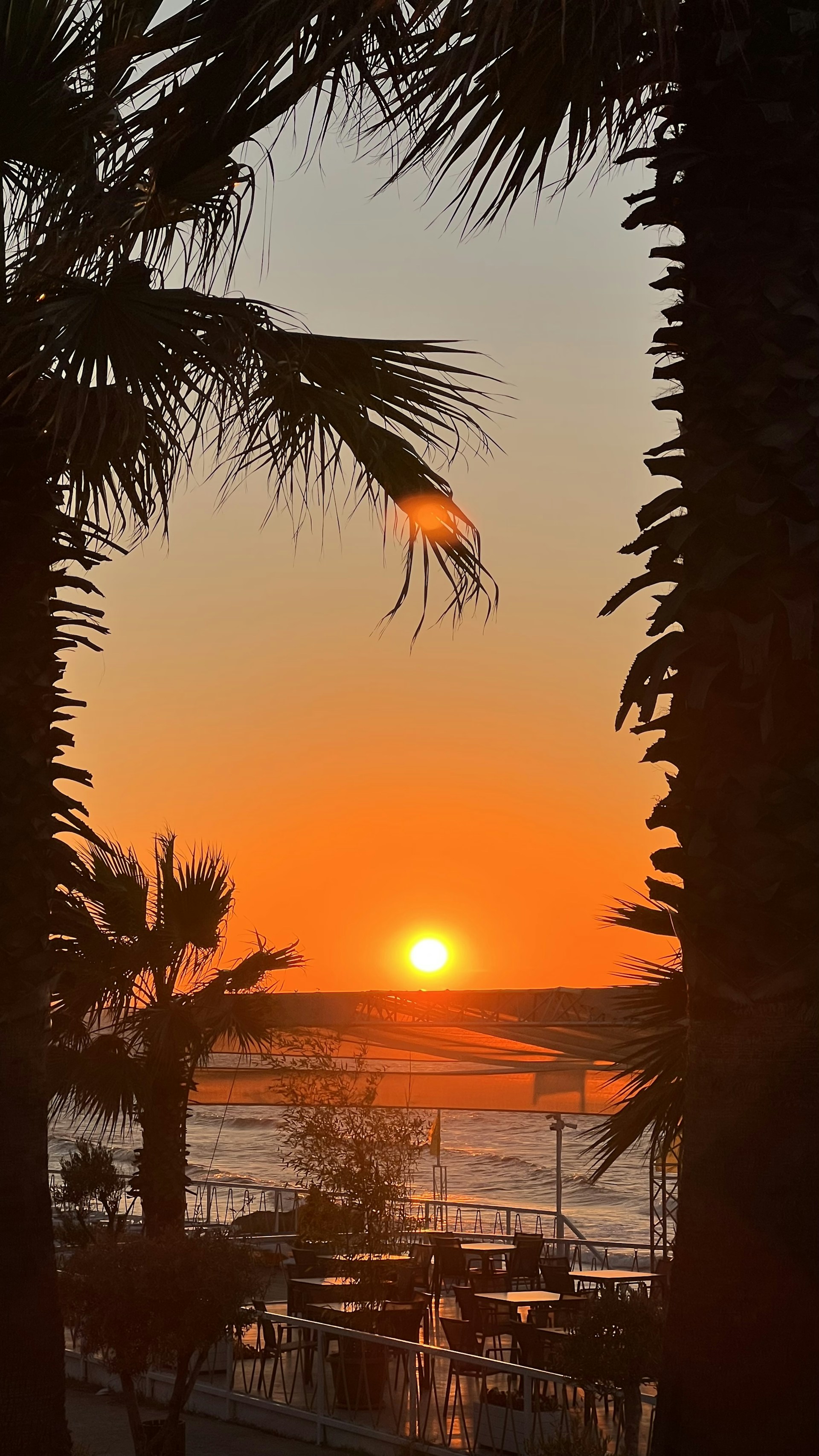 A vibrant sunset view from Nustyak Beach Front Restaurant, showcasing the beach and dining area.