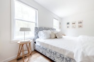 Bright bedroom featuring a queen bed with crisp white linens and a calming blue accent wall.