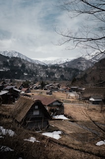 A majestic view of snow-capped peaks rising behind traditional thatched-roof homes.