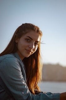 A model walking through a sunlit urban street wearing a clean-cut denim shirt and boots.