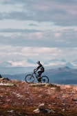 a man riding a bike on top of a grass covered hillside