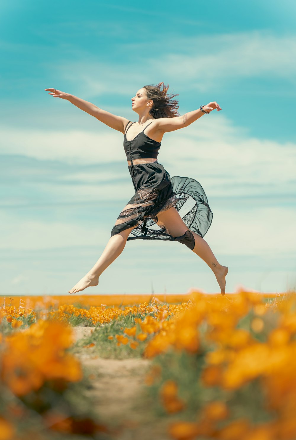 a woman is jumping in the air in a field of flowers