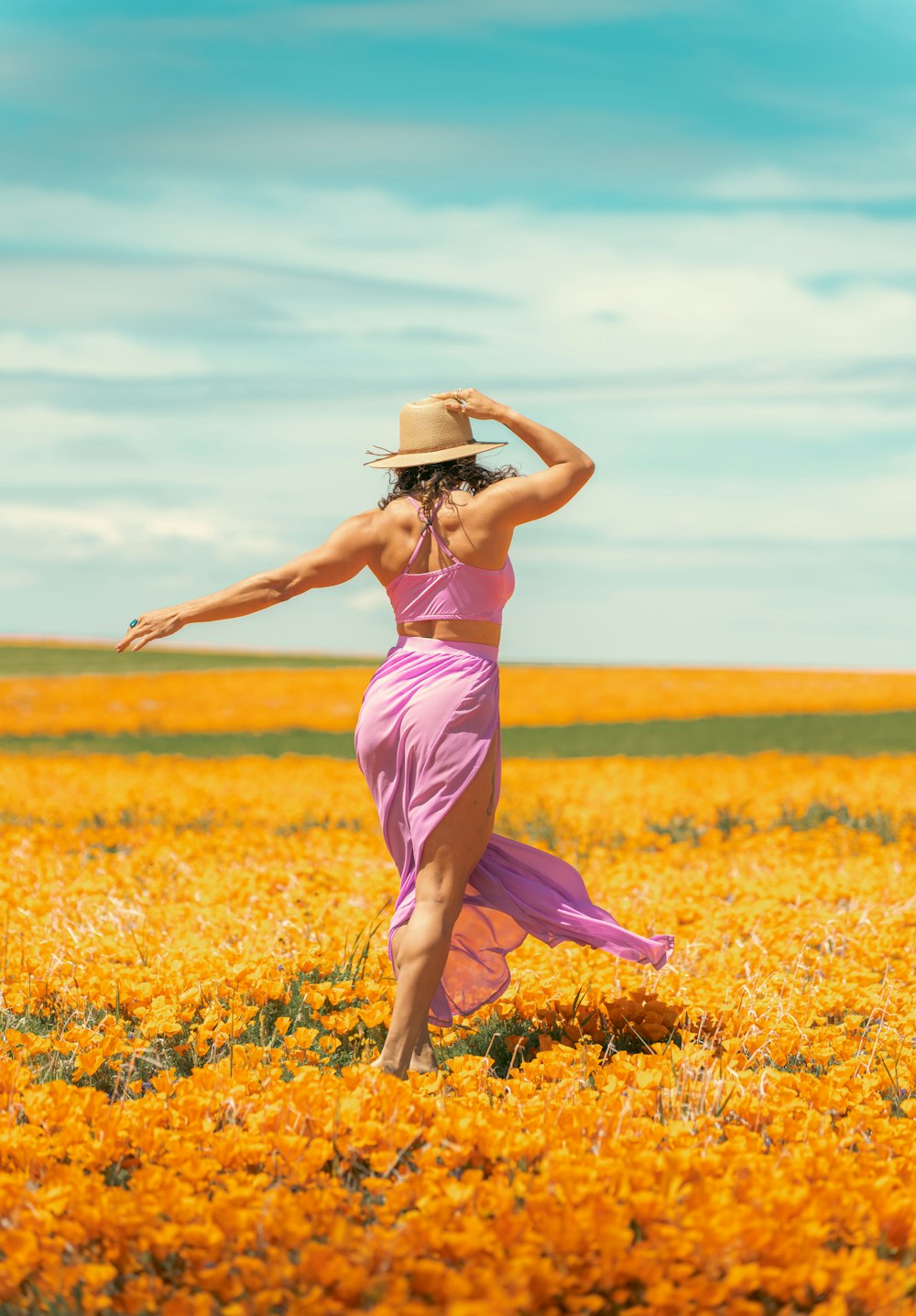 a woman in a pink dress and hat in a field of flowers