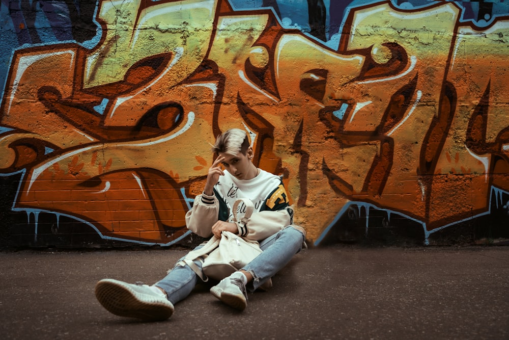 a man sitting in front of a wall covered in graffiti