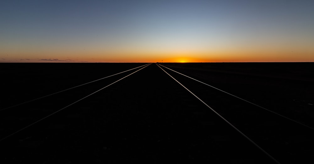 a train track with the sun setting in the background