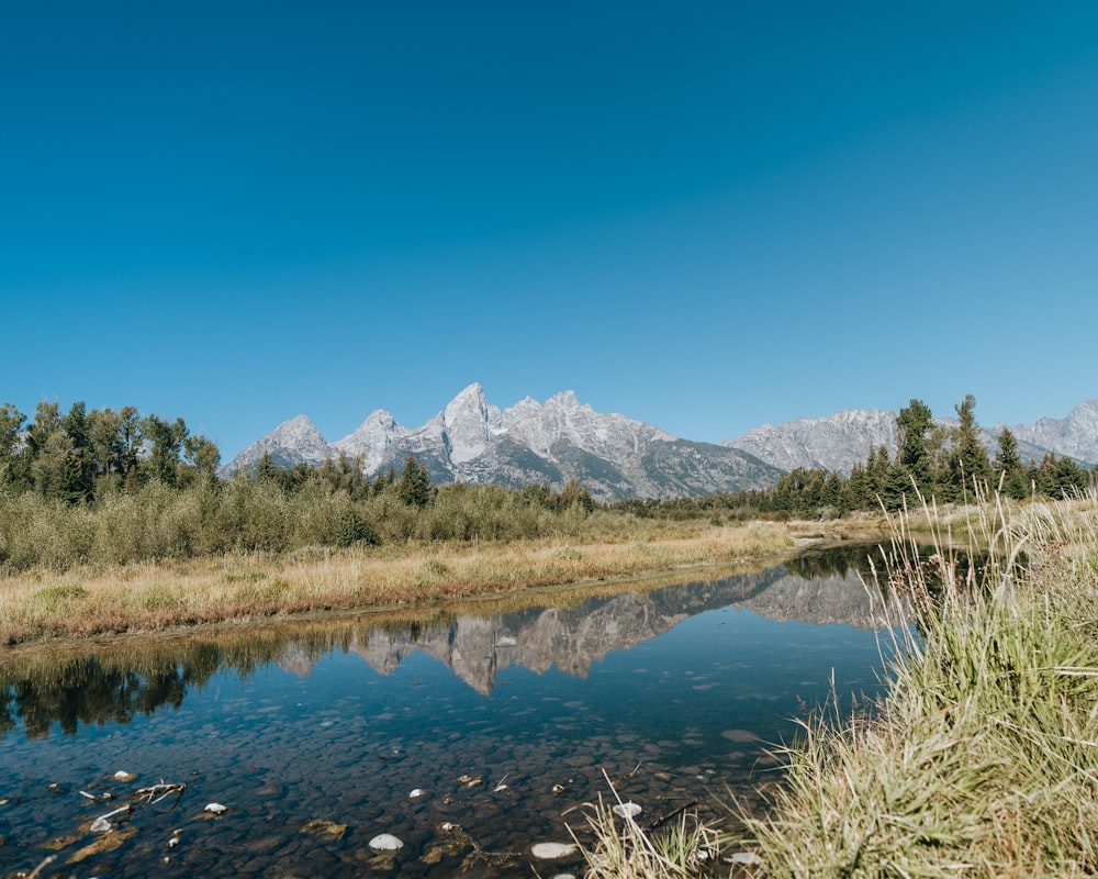 a mountain range is reflected in a river