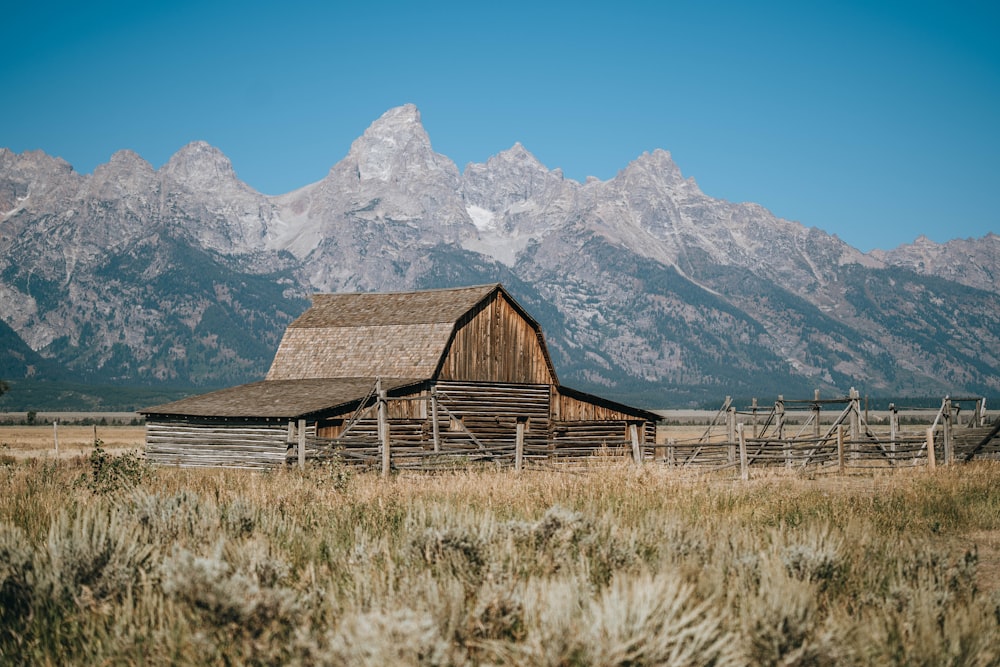 a barn in a field with mountains in the background