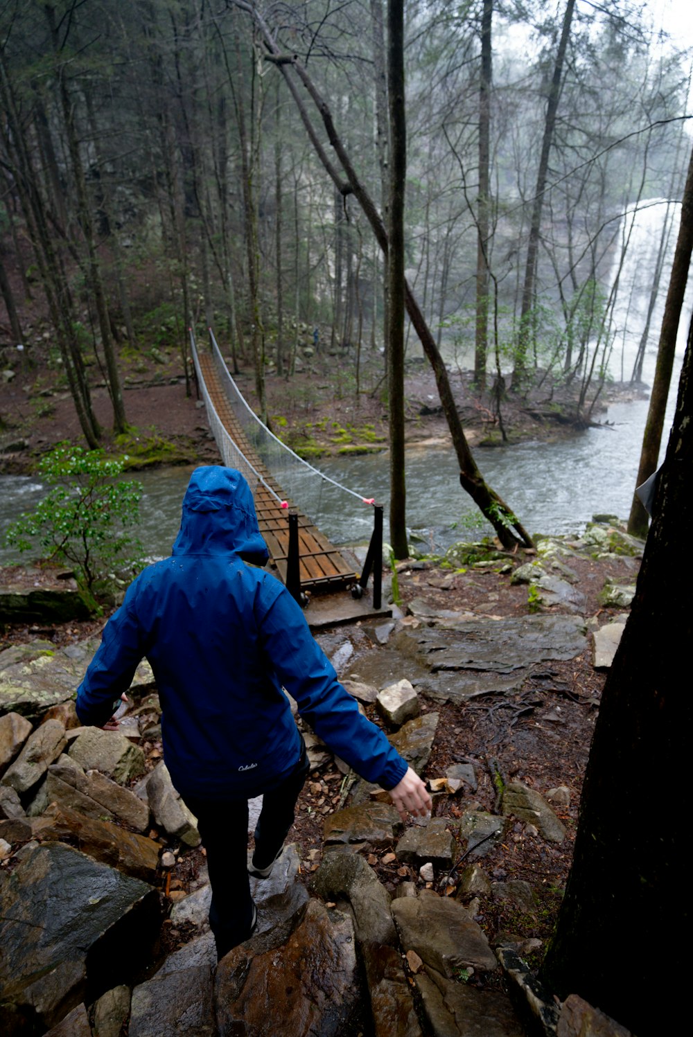 a person in a blue jacket walking across a bridge