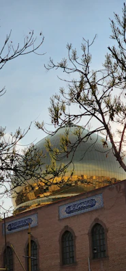 The golden dome of Imam Hussain Shrine glowing warmly at sunset in Karbala.