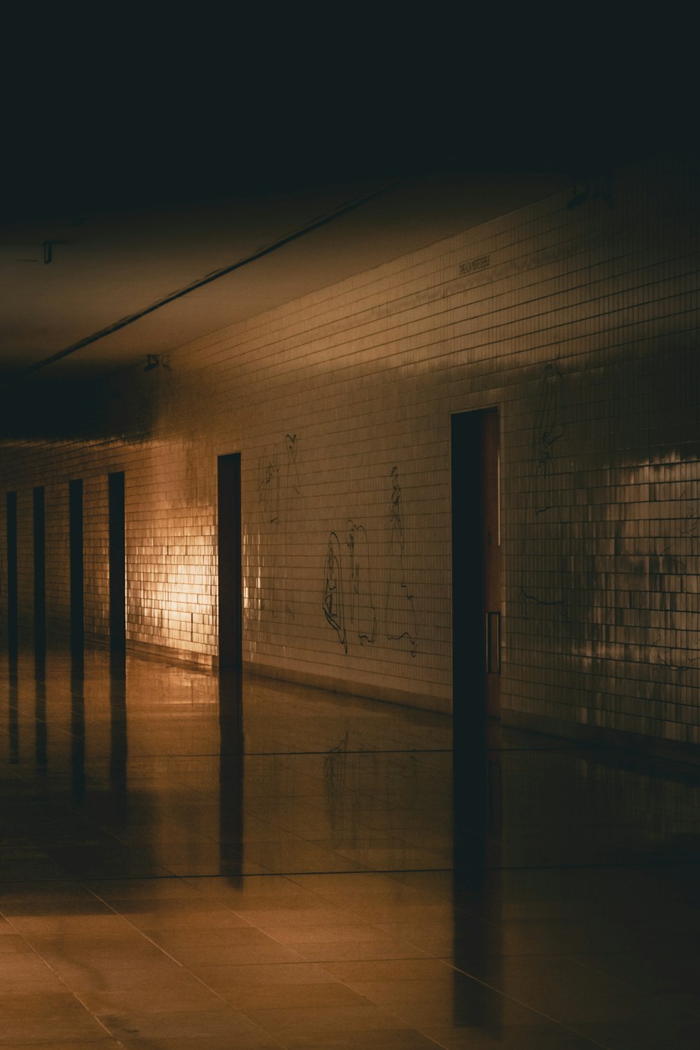 a dimly lit hallway in a building with graffiti on the walls