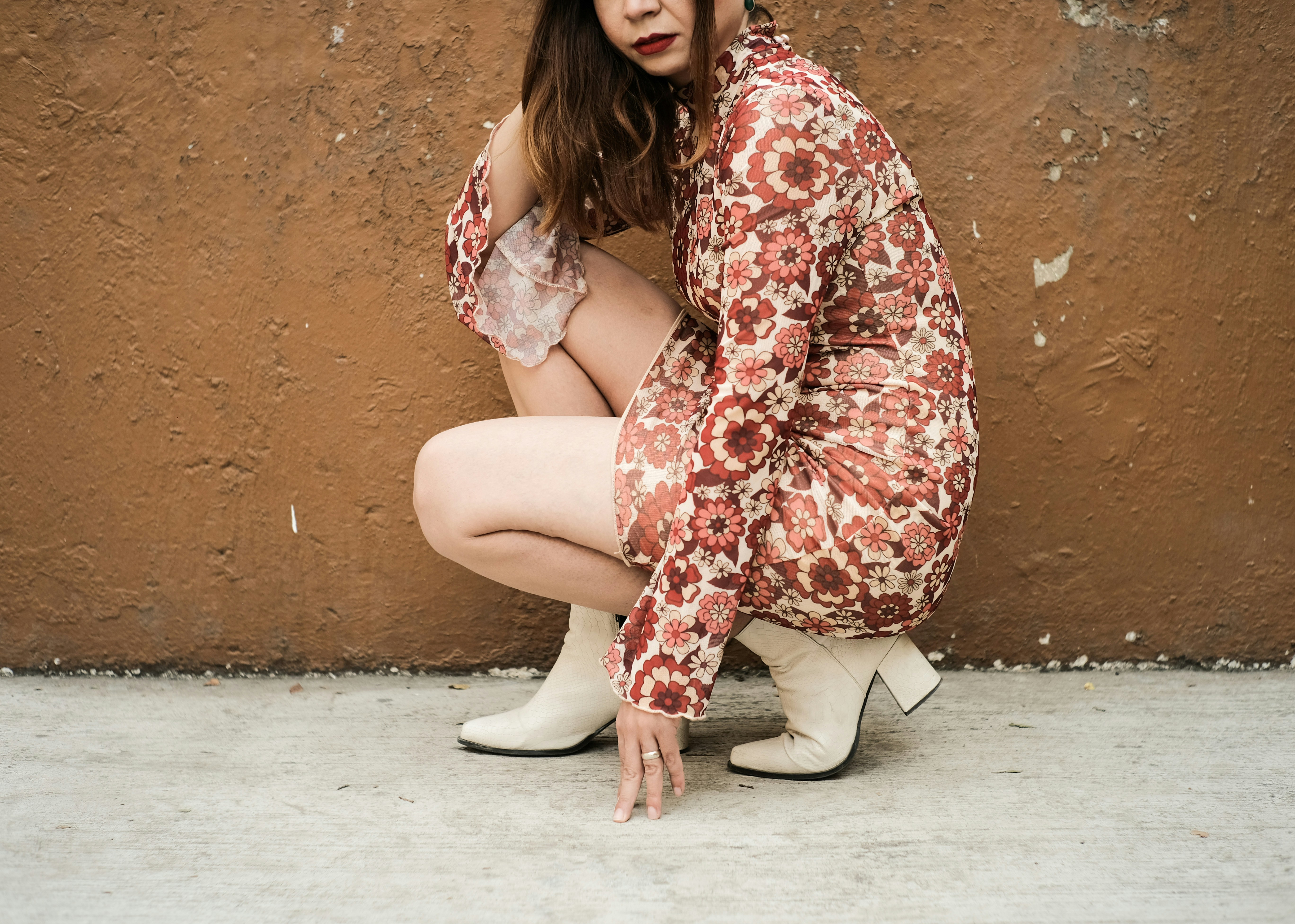 a woman kneeling down in front of a brown wall