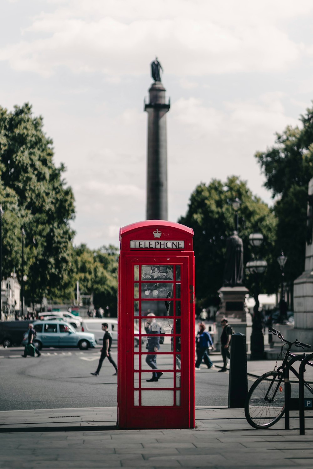 a red phone booth sitting on the side of a road