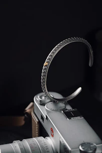 Close-up of a handmade men's leather bracelet resting on a rustic wooden table beside a compass.