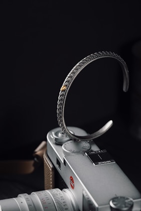 A close-up of a bold leather bracelet with metal accents resting on a textured concrete surface.