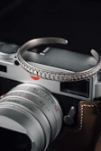 Artistic shot of a hand adorned with Lockend jewelry holding a vintage camera, blending fashion with urban culture.