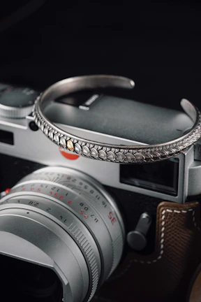 Artistic shot of a hand adorned with Lockend jewelry holding a vintage camera, blending fashion with urban culture.