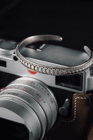 A close-up of delicate silver jewelry alongside a vintage film camera.