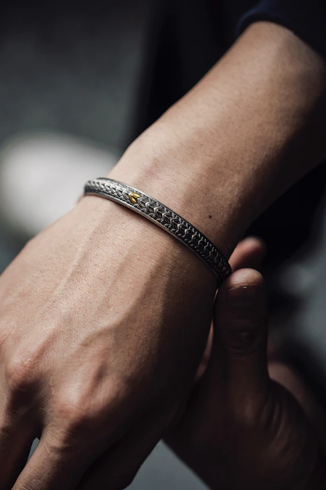 Close-up of a woman's wrist adorned with a thin gold bracelet with small charms, glowing softly in natural light
