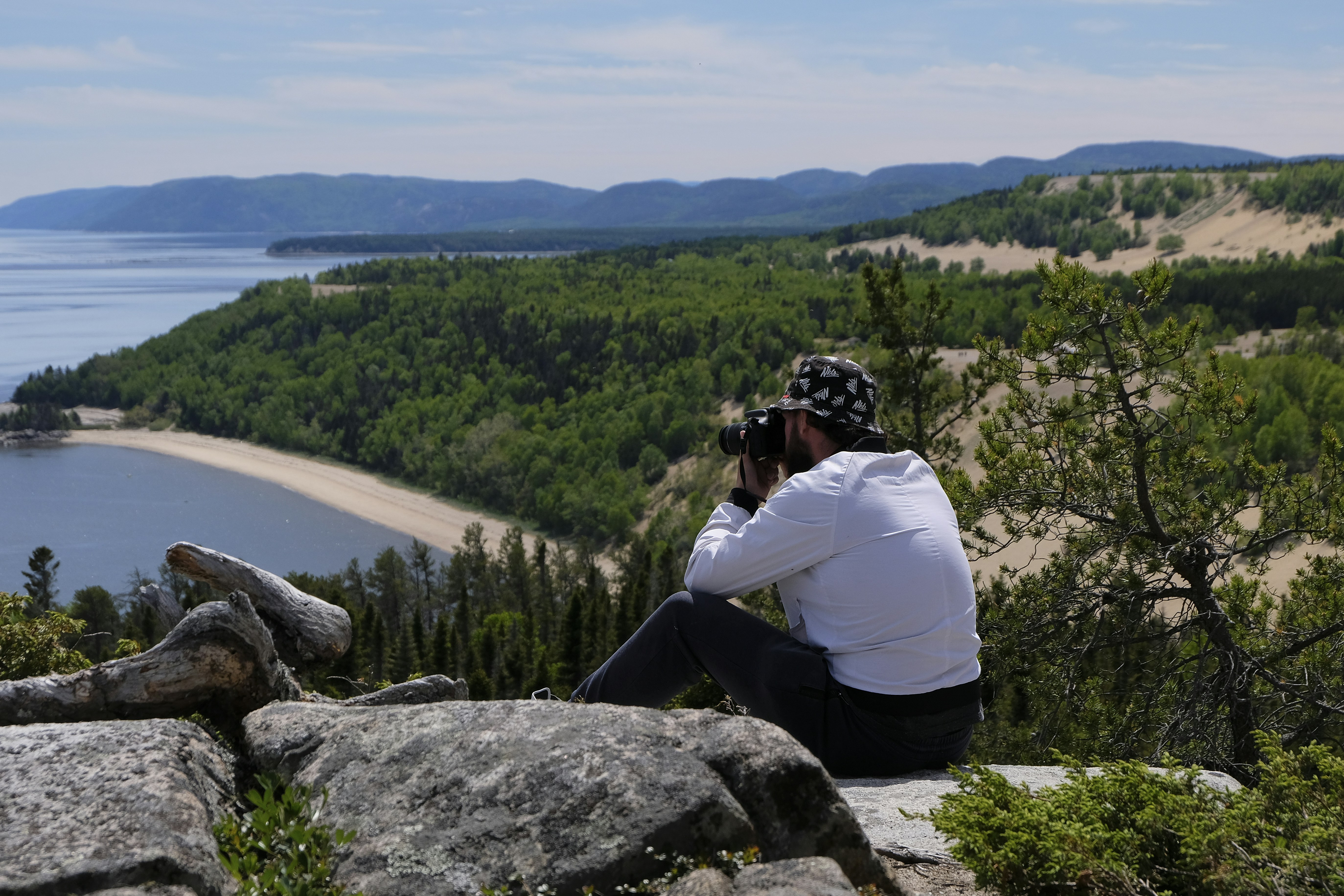 a man sitting on top of a rock next to a forest