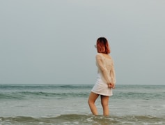 a woman in a white dress standing in the ocean