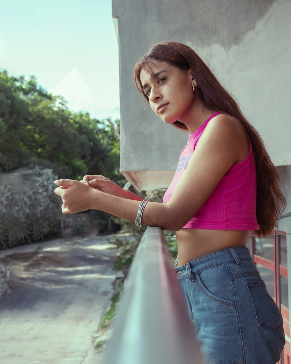 a woman in a pink shirt leaning against a wall