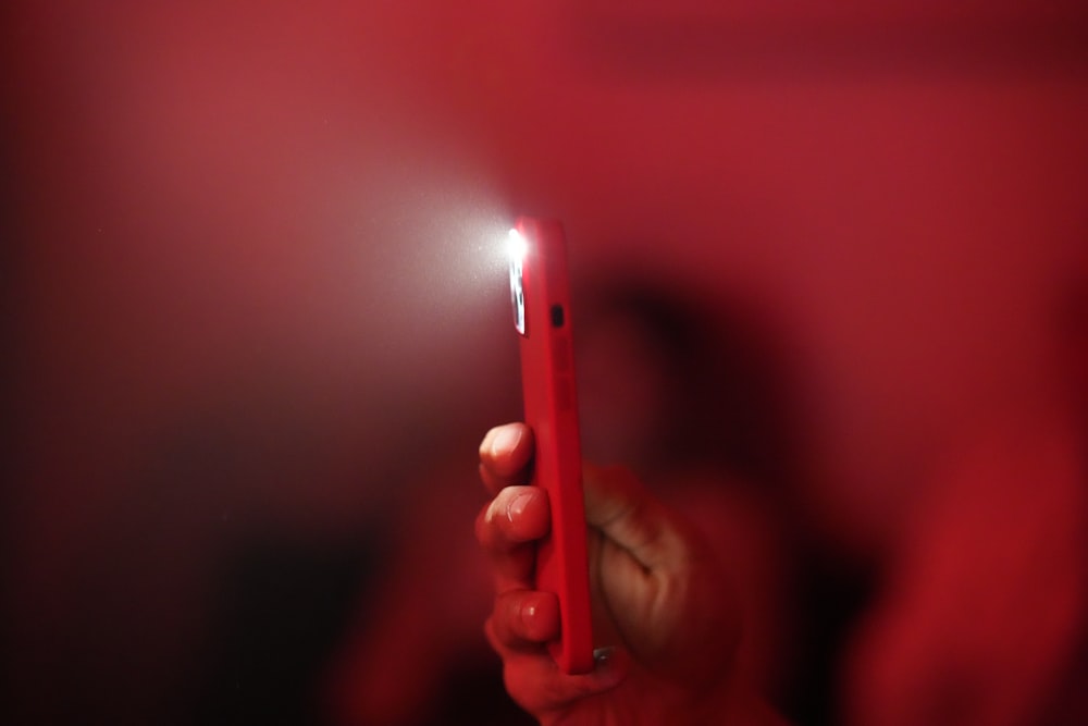 a person holding a red lighter in their hand