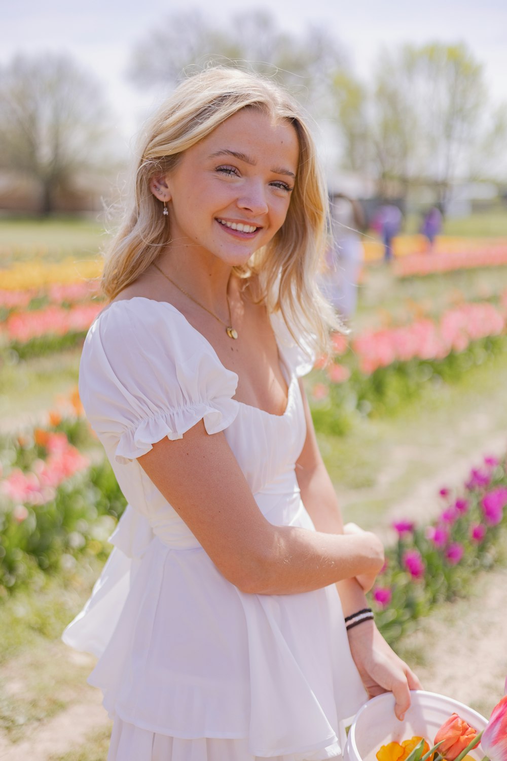 a woman in a white dress holding a basket of flowers