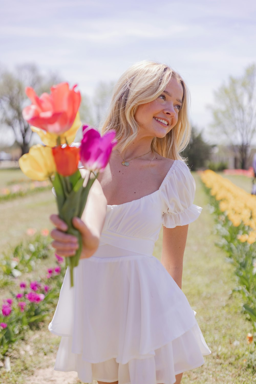 Une femme en robe blanche tenant un bouquet de fleurs