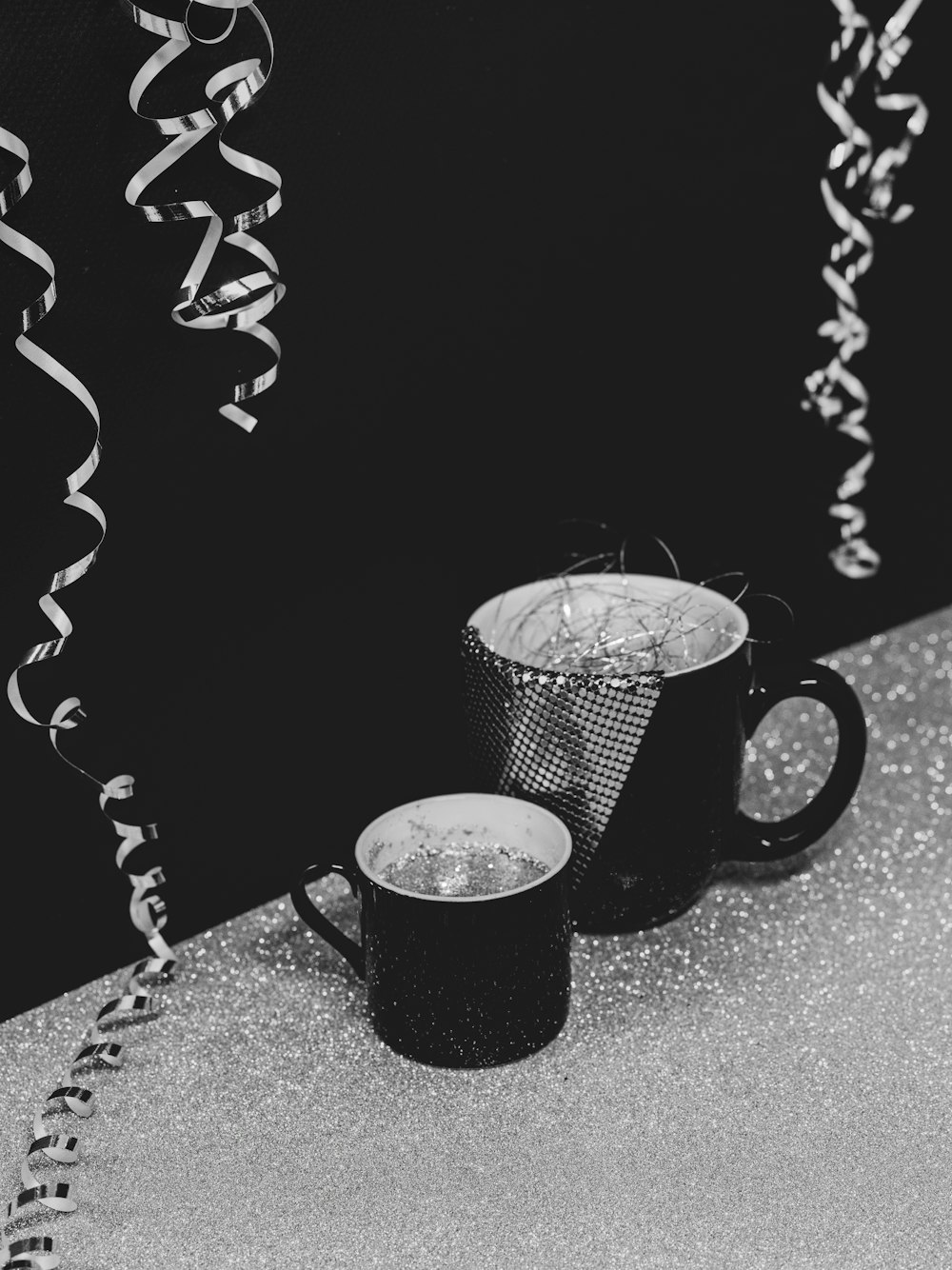 a black and white photo of two coffee mugs