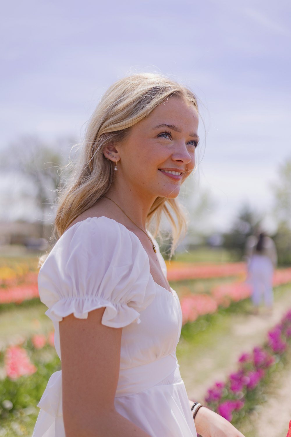 a woman in a white dress standing in a field of flowers