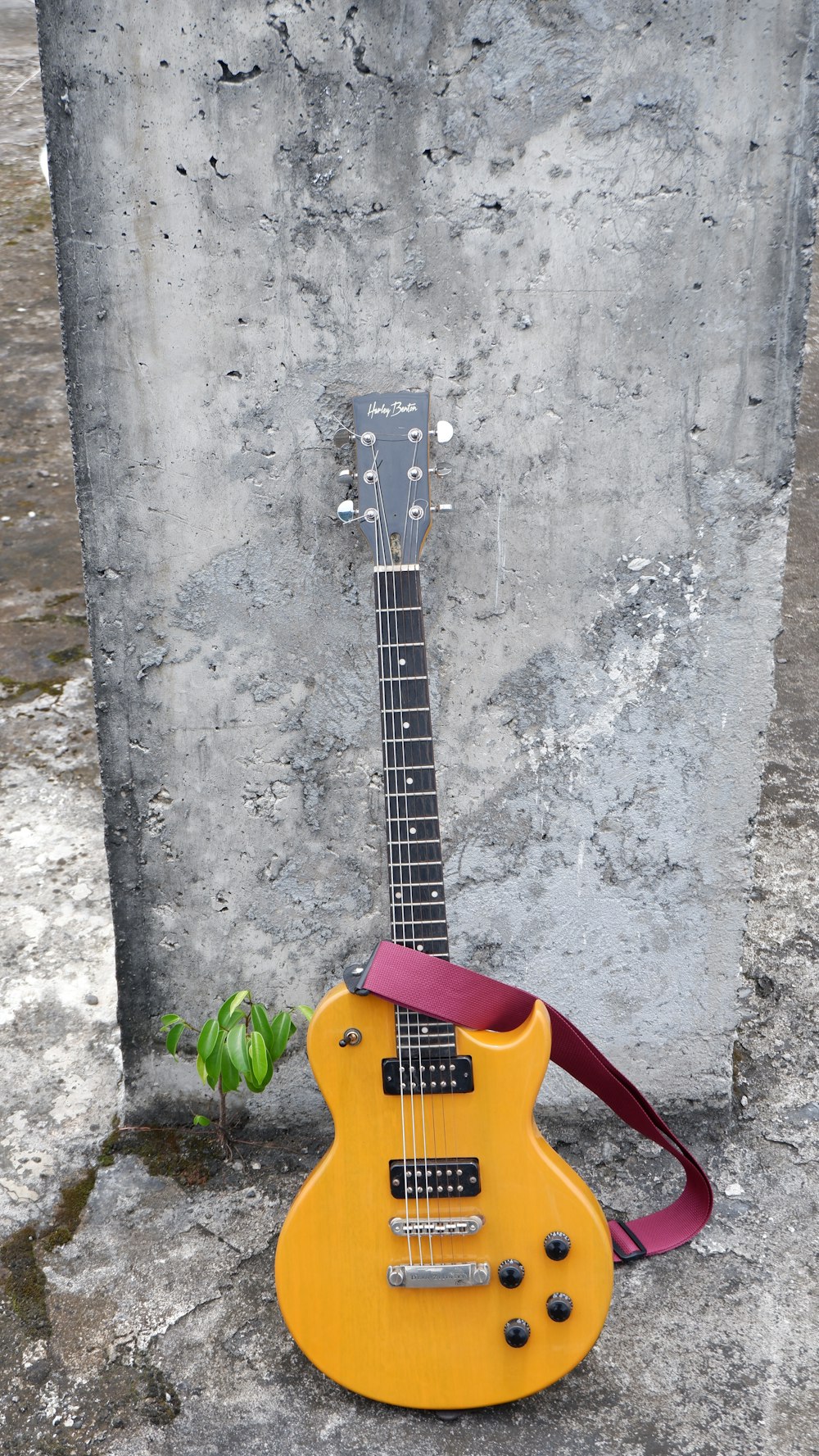 a yellow guitar sitting on top of a cement wall