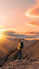 A hiker wearing Ryvo activewear standing on a mountain overlook at sunrise.