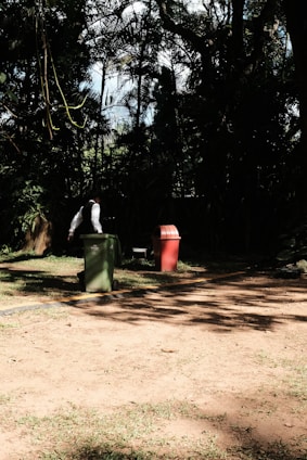 A friendly binrangers team member helping an elderly resident by moving bins to the curb on a sunny suburban street.