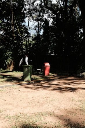 A friendly Binrangers team member helping an elderly woman wheel her bins to the curb on a sunny morning.